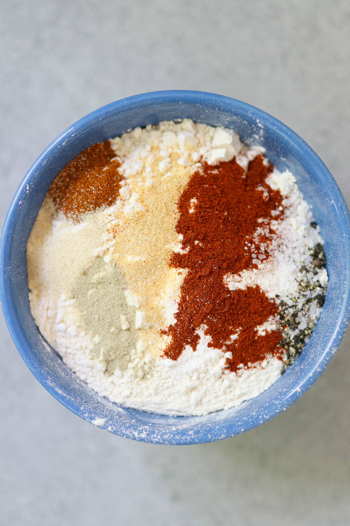 Photo of the spices with the flour before mixing, in a blue bowl