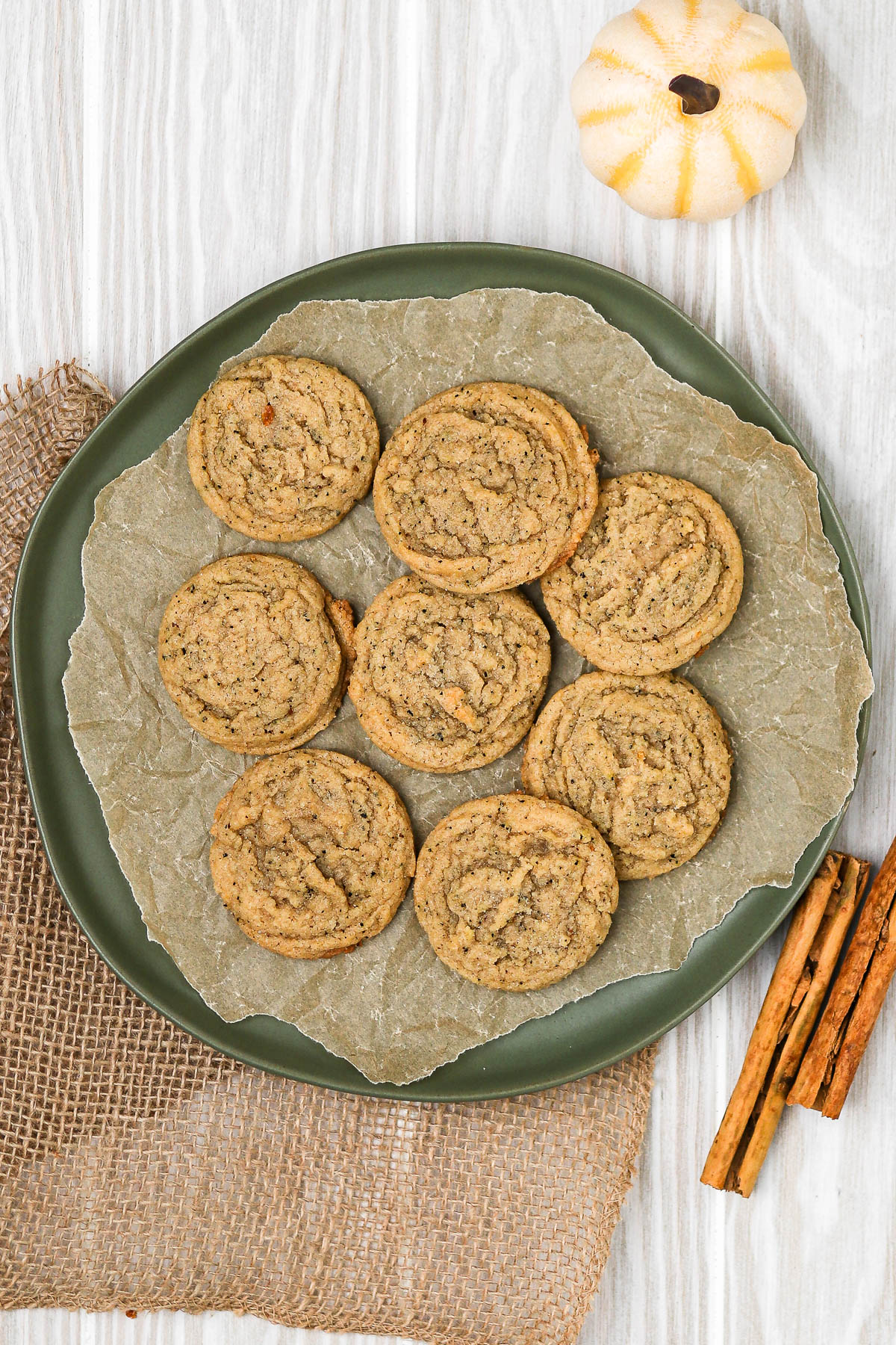 chai cookies on a green plate with pumpkin and cinnamon sticks.