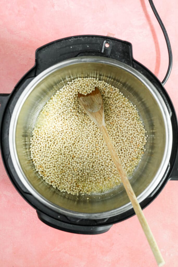 dry couscous in the instant pot with wooden spoon.