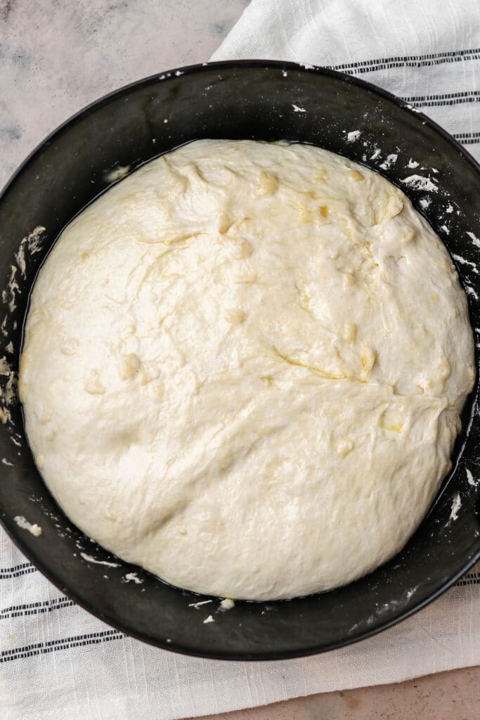 dough in a large black bowl after doubling in size.