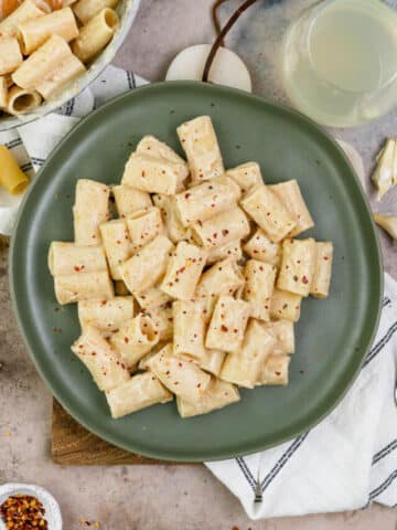 tahini pasta on a green plate with garnishes around.