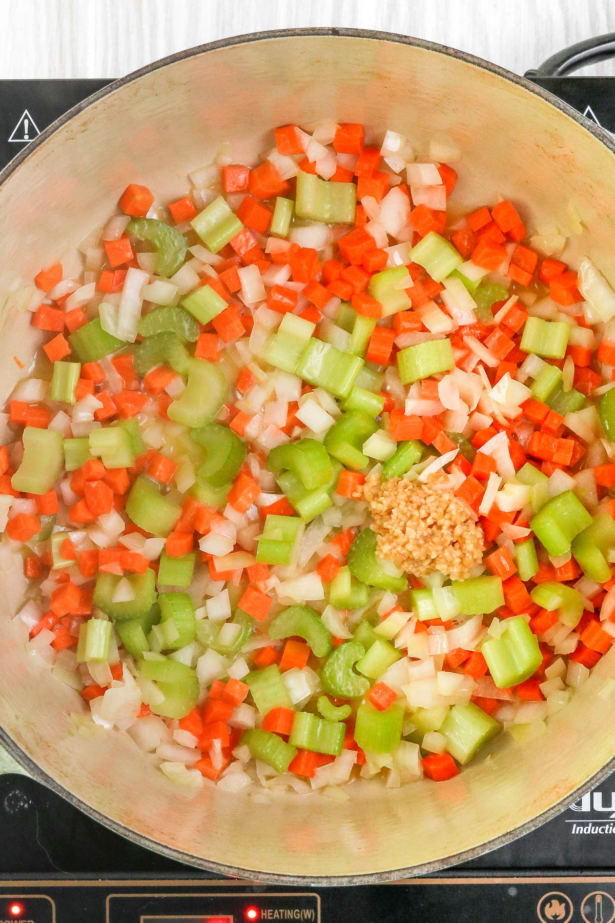 onion, carrot, celery, and garlic mixed together in a large pot.