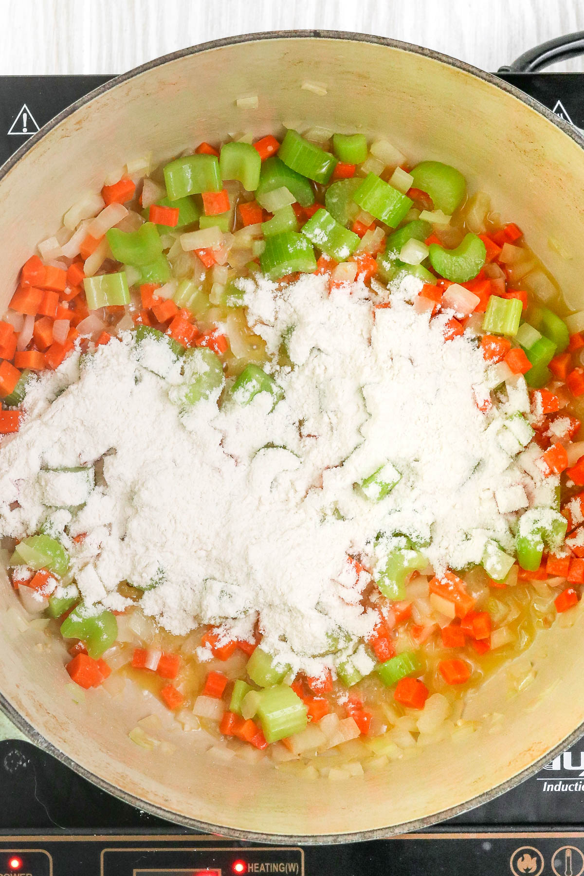 flour on top of mixed vegetables in large pot.