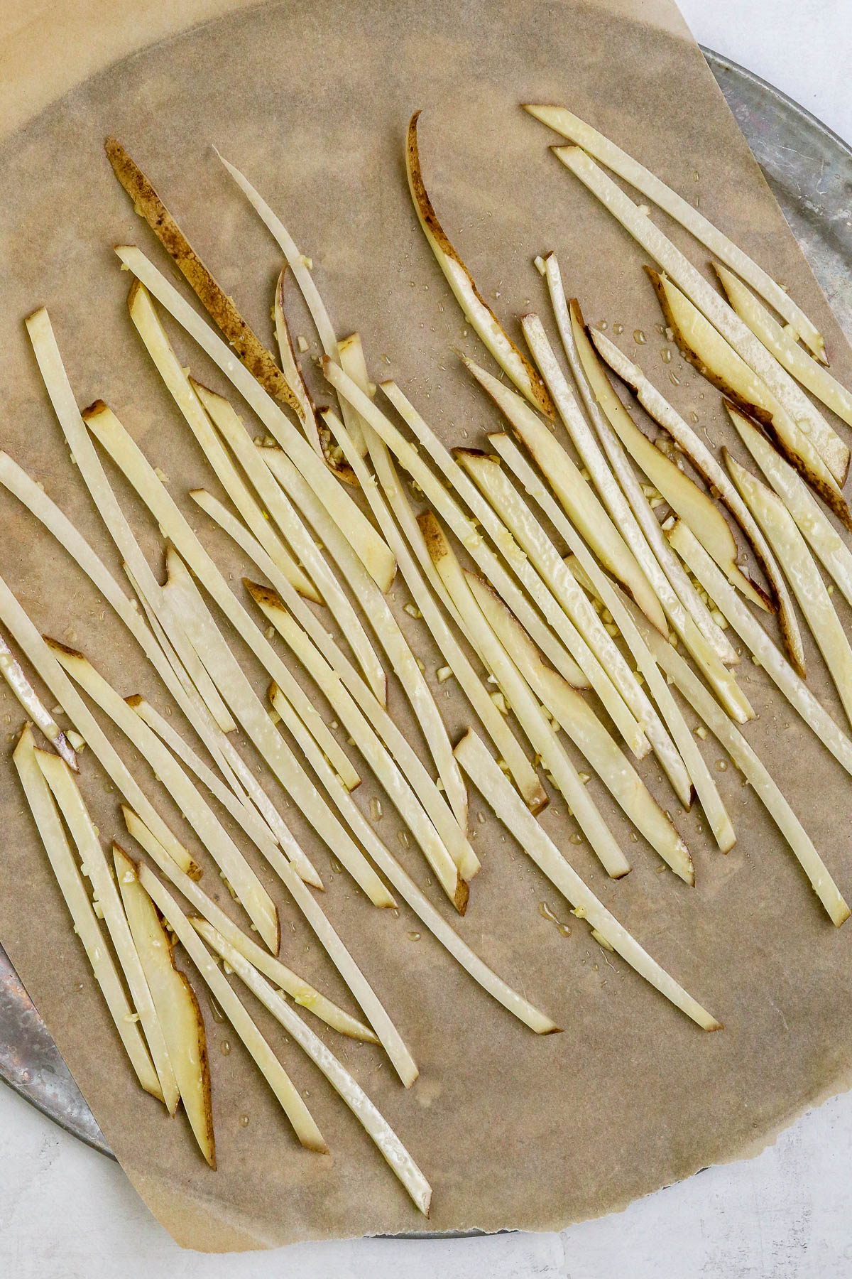 unbaked fries on a baking sheet.