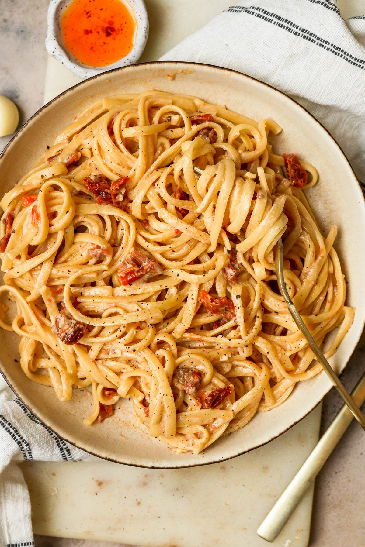 tomato pasta in a white bowl with a fork in the pasta.