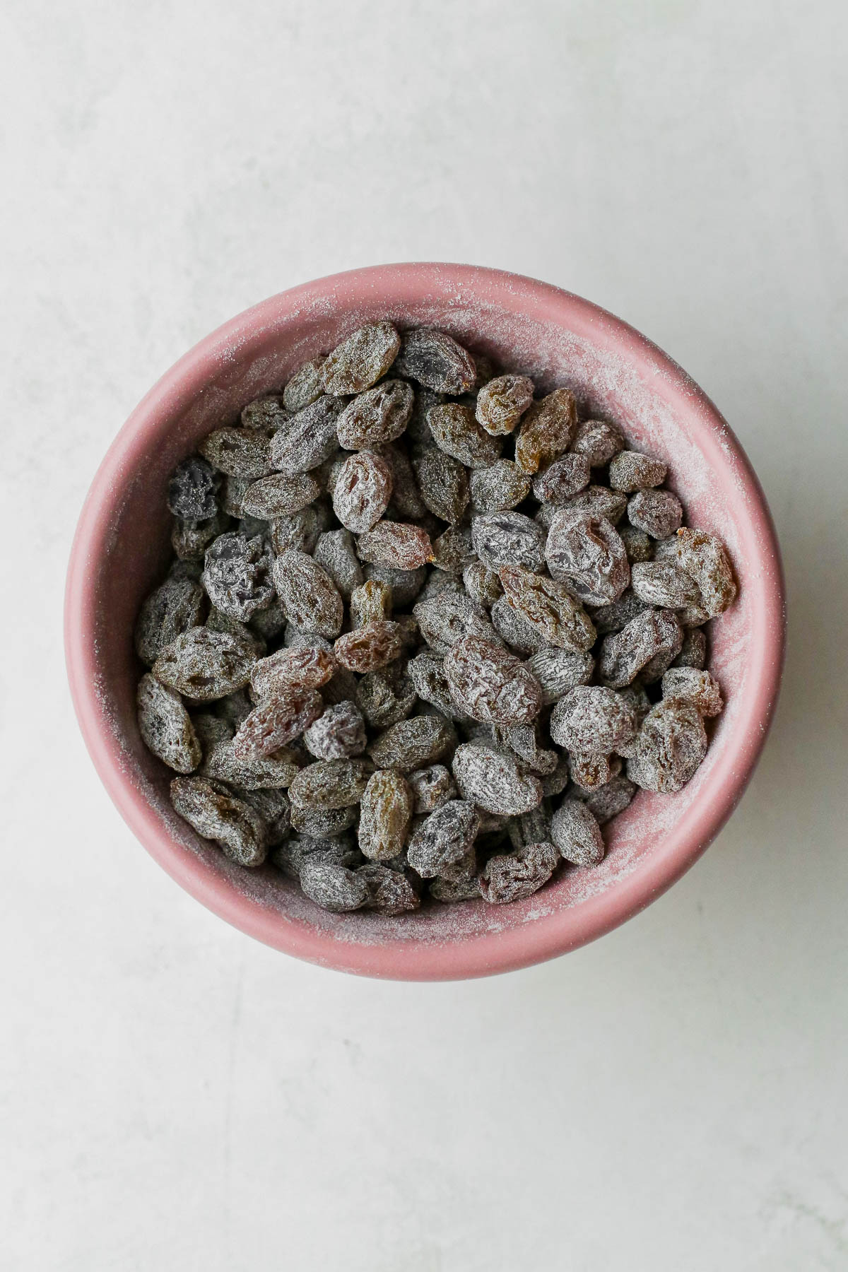 raisins coated in flour in a pink bowl.