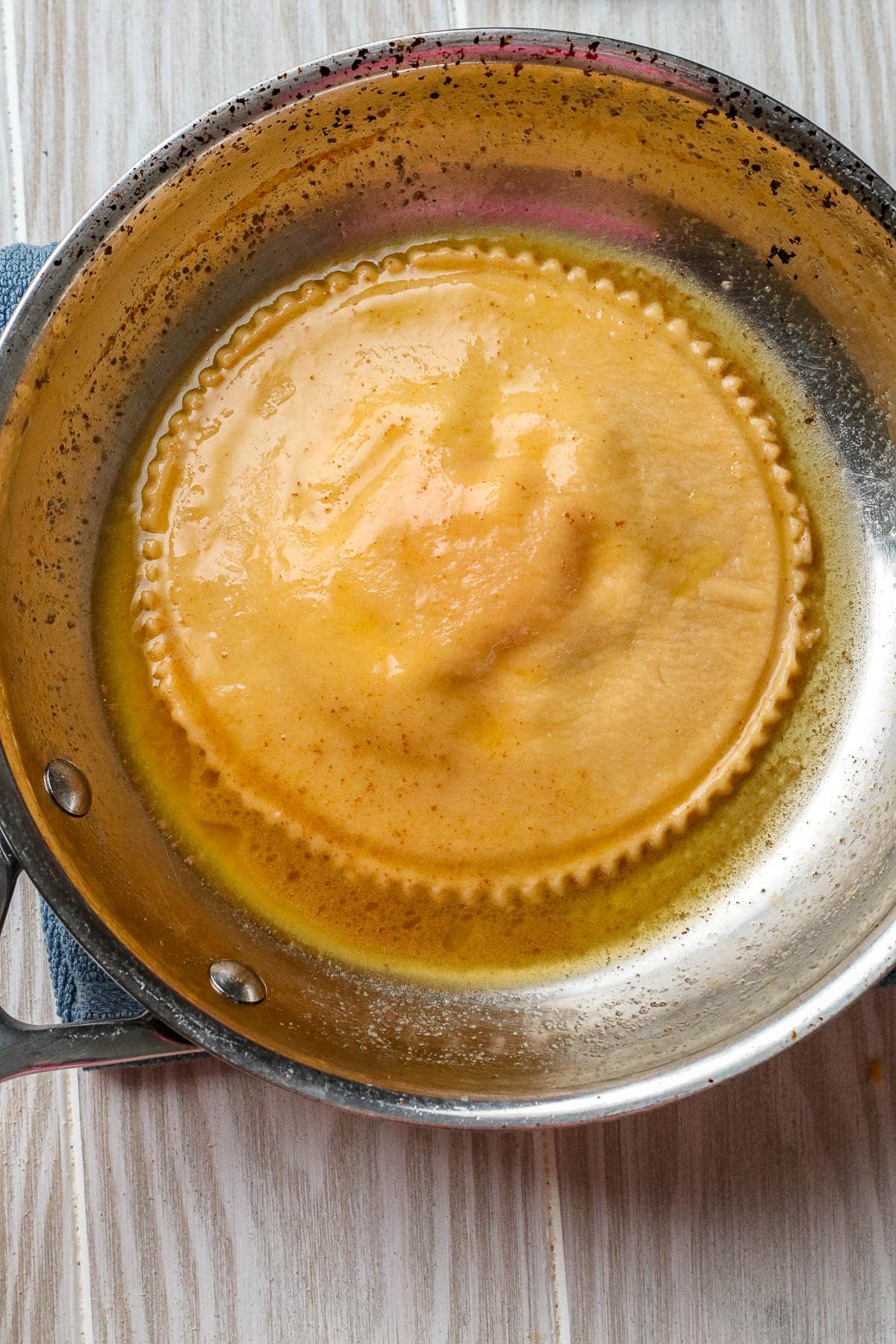 cooked raviolo in a pan with brown butter sauce.