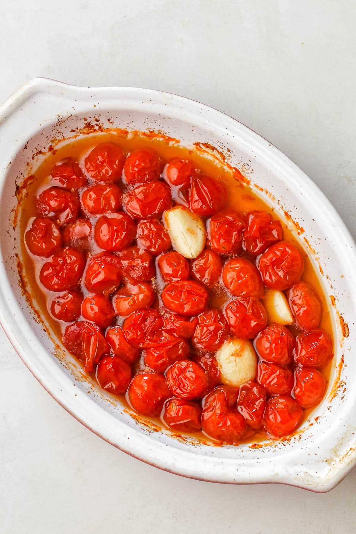 roasted tomatoes and garlic in a white baking dish.