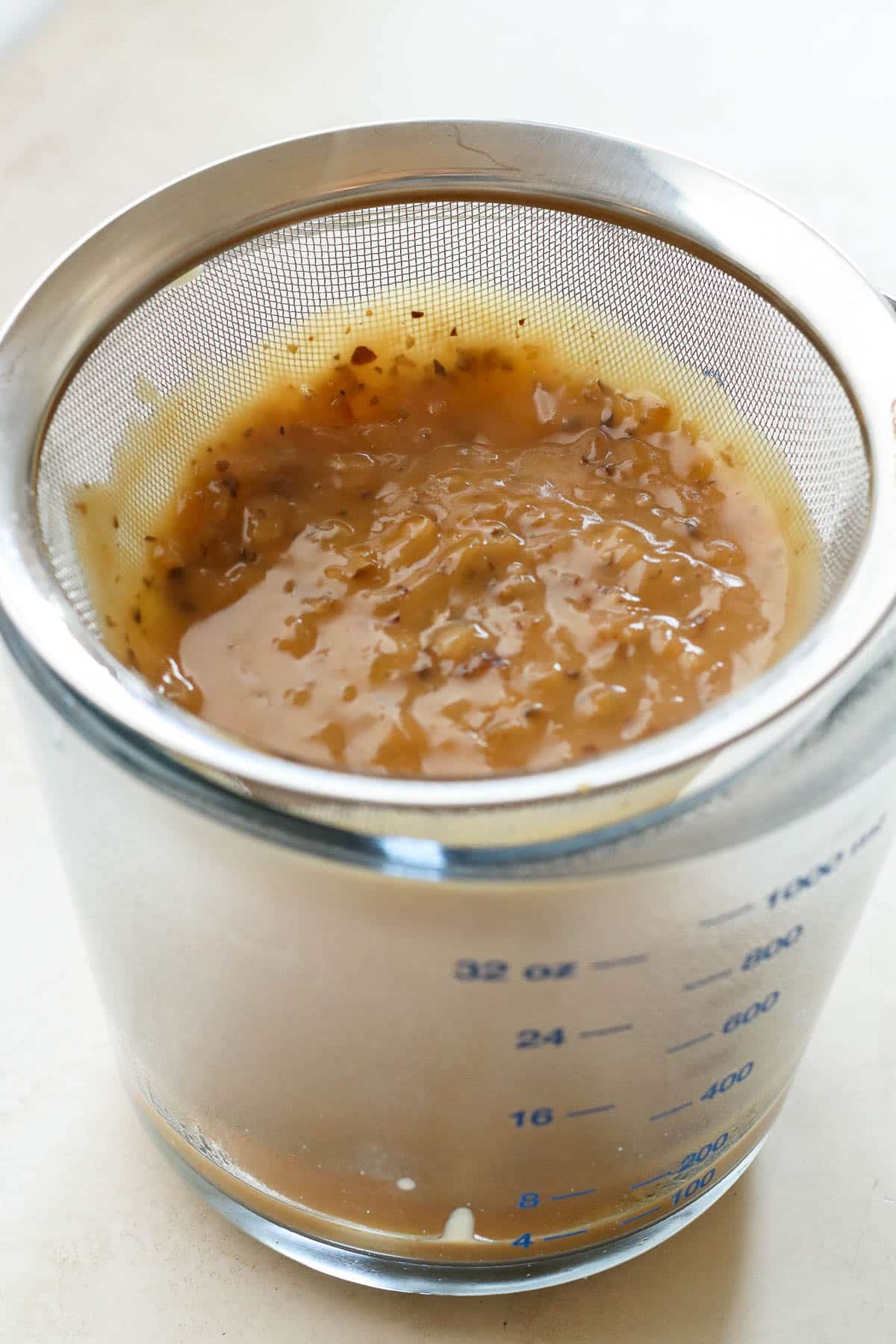 gravy straining over measuring cup.
