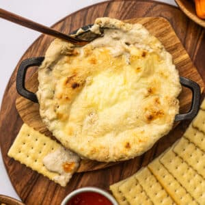 crab rangoon dip in a pot with crackers and sauce.